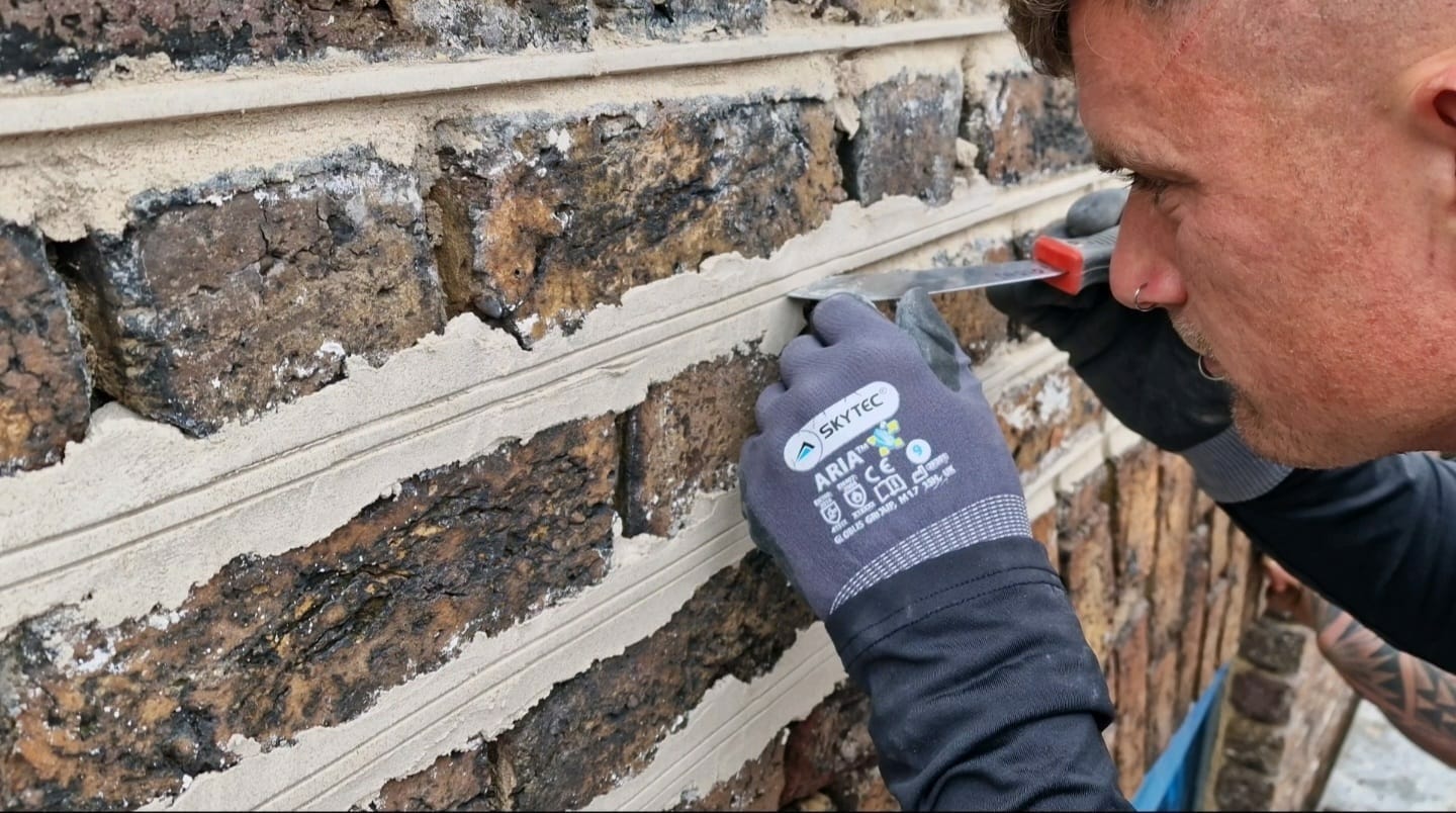 PMAC operative working repointing house with new mortar